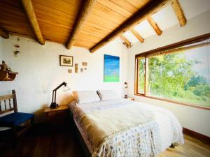 a bedroom with a bed and a large window at Varsovia, chalet, hospedaje in Guatavita
