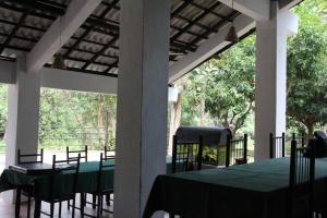 ein Esszimmer mit einem Tisch und Stühlen auf einer Veranda in der Unterkunft Dambulu Oya Family Park in Dambulla