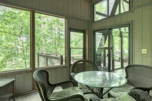 un porche cubierto con mesa de cristal y sillas en Woodland Getaway Chalet, en Innsbrook
