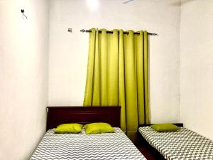 2 letti in una camera con tende verdi di Yu Home Stay Anuradhapura a Anuradhapura