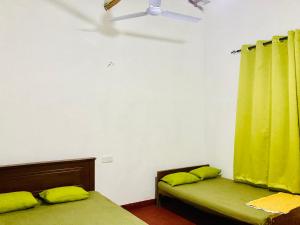 una camera con due letti e una tenda verde di Yu Home Stay Anuradhapura a Anuradhapura