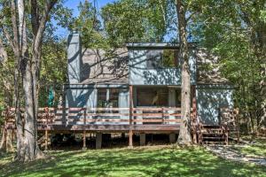a house sitting on a deck in the woods at Lakefront A-Frame with Private Dock in Innsbrook