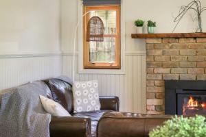 a leather couch in a living room with a fireplace at Spring Creek Cottage in Beechworth