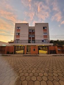 a building with a sunset in front of it at Sapucaia Flat - Apart Hotel in Santa Rita do Sapucaí