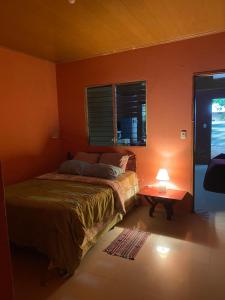 リバスにあるAlojamiento en Rivasのオレンジ色の壁のベッドルーム1室、ベッド1台、テーブルが備わります。