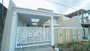 a house with a gate and a fence at Guest House Jogja Lempongsari in Kejayan