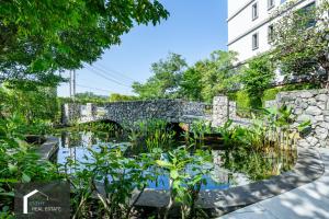 un pont en pierre sur un étang en face d'un bâtiment dans l'établissement Cozy Studio Apartment at Naiyang Beach G507, à Phuket