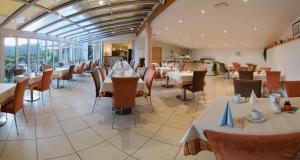 un comedor con mesas, sillas y ventanas en Garni Hotel Sonnleitenhof, en Caldaro