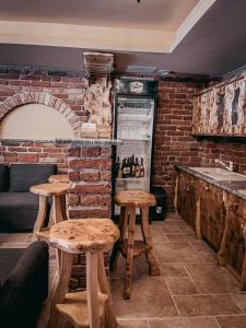 a bar with wooden stools and a brick wall at Rönkház Noszvaj in Noszvaj