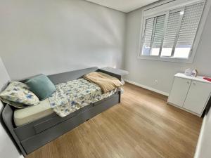 a small bedroom with a bed and a window at Lindo apartamento no centro de Canoas in Canoas
