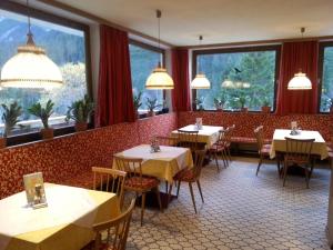 ein Restaurant mit Tischen und Stühlen und großen Fenstern in der Unterkunft Gasthof Bergheimat in Boden