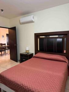 ein Schlafzimmer mit einem großen Bett mit einer roten Bettdecke in der Unterkunft Acogedor depaetamento por estadio Dorados in Casas