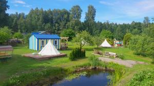 a group of tents in a field with a pond at Glamping Fluffy Horns - Glempings Pūkainie Ragi in Plieņciems