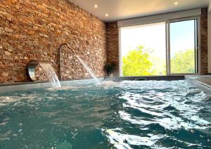 una piscina coperta con fontana in un muro di mattoni di Hotel Agian - Maison Bonnet a Itxassou
