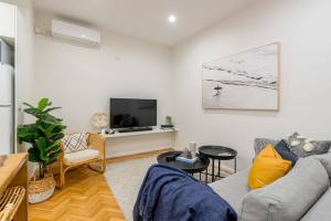 a living room with a couch and a tv at Coastal Nest - Stylish 1BR Steps to Towradgi Beach in Towradgi