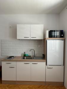 a kitchen with white cabinets and a sink and a refrigerator at Beach House Murter in Murter