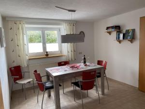 a dining room with a table and red chairs at Ferienwohnungen Wentzler in Pflach +7 photos