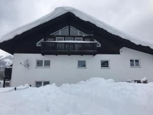 a building covered in snow with a balcony on it at Ferienwohnungen Wentzler in Pflach