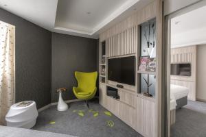 una camera da letto con una sedia gialla e una TV di Stanford Hillview Hotel Hong Kong a Hong Kong