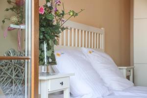a white bed with a vase of flowers on a table at Laguna Resort in Budzisław