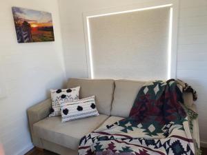 a couch with two pillows and a blanket on it at Gem View - Tiny home in Barwite