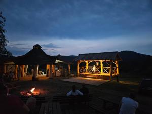 a group of people sitting around a fire at night at Perełka Bieszczady Domki in Cisna
