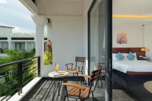 a bedroom with a balcony with a bed and a table and chairs at Khmer House Boutique in Siem Reap