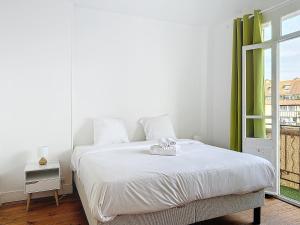 a white bedroom with a bed and a window at Urban Haven in Deauville +10 photos
