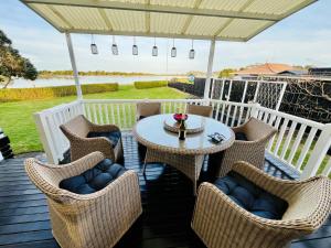 eine Terrasse mit Tisch und Stühlen auf einem Deck in der Unterkunft Monarch Cottage on the Estuary in Athenree + 4 Fotos