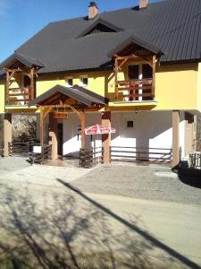 a yellow house with a black roof with an umbrella at Apartment Ana Marija in Mavrovo