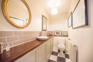 een badkamer met een wastafel, een toilet en een spiegel bij Olive Cottage, Wickham Market in Wickham Market +25 foto's