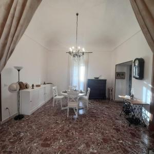 a dining room with a table and chairs and a chandelier at La Cortese, cuore barocco in Noto