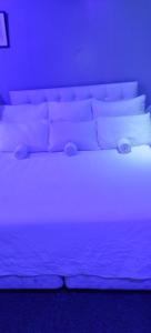 Cama blanca en habitación con luz azul en Royal Guest House & and Lodge, en Pietermaritzburg