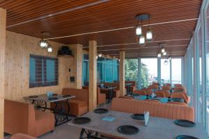a restaurant with tables and chairs and windows at The Sarbati Palace Hotel in Kanatal