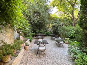 a patio with tables and chairs in a garden at Le Clos Saluces in Avignon