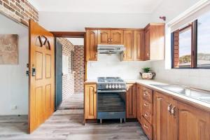 a kitchen with wooden cabinets and a stove top oven at Chic Queen Room - Nearby Station & Olympic Park - Shared Bathroom in Regents Park +27 photos