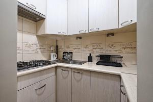a kitchen with white cabinets and a sink and a stove at UrbanNest - Cozy studio - Bagno 7 in Warsaw