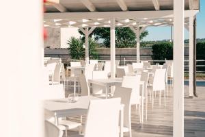 a row of white tables and chairs on a patio at Zyra Garden Club in Acquaviva delle Fonti