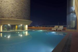 a swimming pool with chairs and a building at night at Vesta International in Jaipur