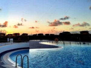 a large swimming pool with a sunset in the background at La casita de Taty in Majanicho