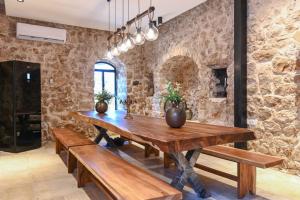 a dining room with a wooden table and benches at קונפיטה - וילה מהממת ובריכה בעיר העתיקה צפת in Safed