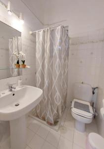 a white bathroom with a toilet and a sink at Poros Pine View in Poros +37 photos