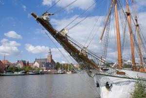 a sail boat docked in a river with a city at Hotel Hafenspeicher in Leer