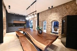 uma grande cozinha com uma mesa de madeira e uma parede de pedra em קונפיטה - וילה מהממת עם בריכה מחוממת מקורה בעיר העתיקה צפת em Safed