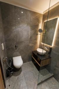 a bathroom with a toilet and a glass shower at Mannat Residency By iO Hotels Near Golden Temple in Amritsar +17 photos