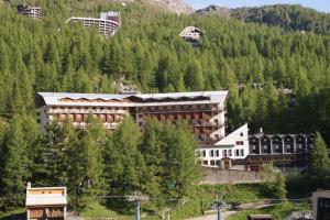 a large building in front of a mountain with trees at Luxury flat in Cervinia 34 in Breuil-Cervinia