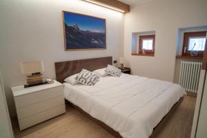 a bedroom with a white bed with a nightstand and a bed sidx sidx sidx at Luxury flat in Cervinia 34 in Breuil-Cervinia