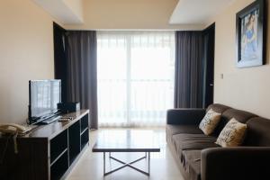 a living room with a couch and a tv at Best Location 2BR at Braga City Walk Apartment By Travelio in Bandung