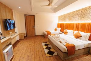a hotel room with two beds and a flat screen tv at Mannat Residency By iO Hotels Near Golden Temple in Amritsar