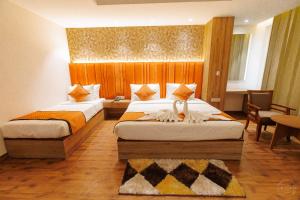 a hotel room with two beds and a table and chairs at Mannat Residency By iO Hotels Near Golden Temple in Amritsar